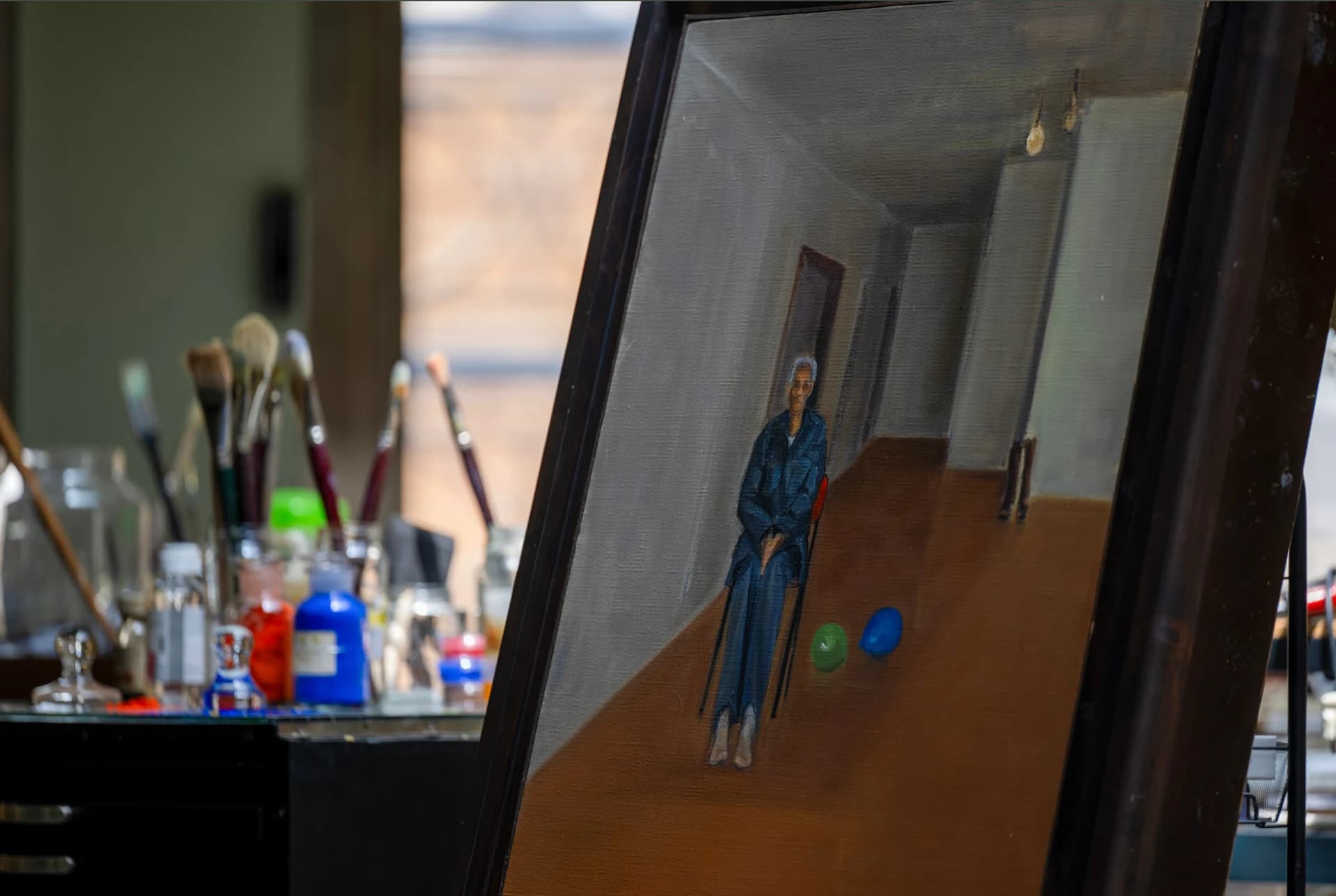 A portrait on the easel beside brushes and pigments